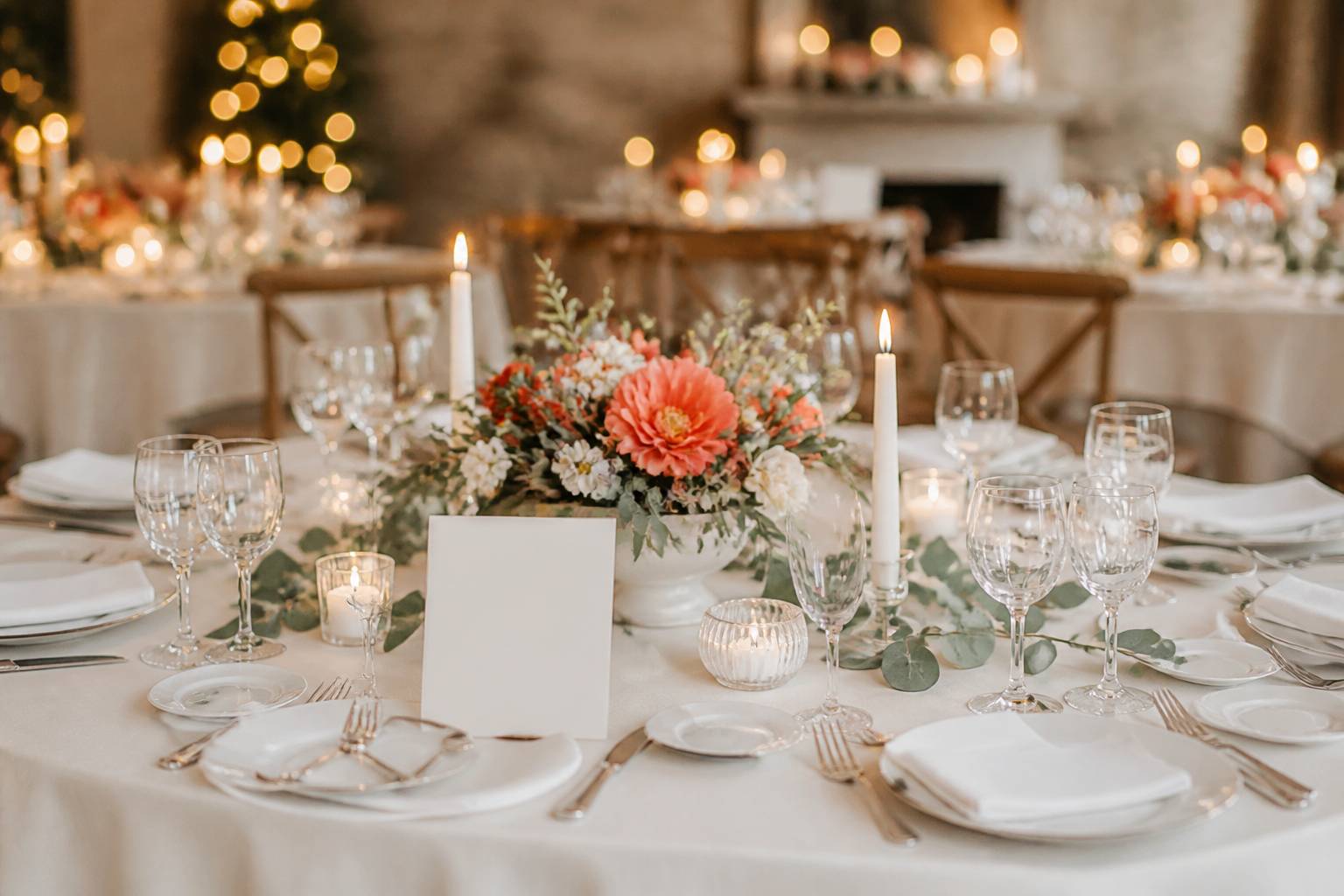 Table de mariage dressée avec vaisselle blanche, verres et composition florale corail