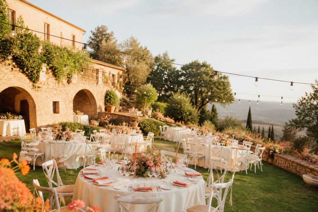 Villa en pierre avec jardin et tables rondes dressées pour un mariage sur une colline italienne