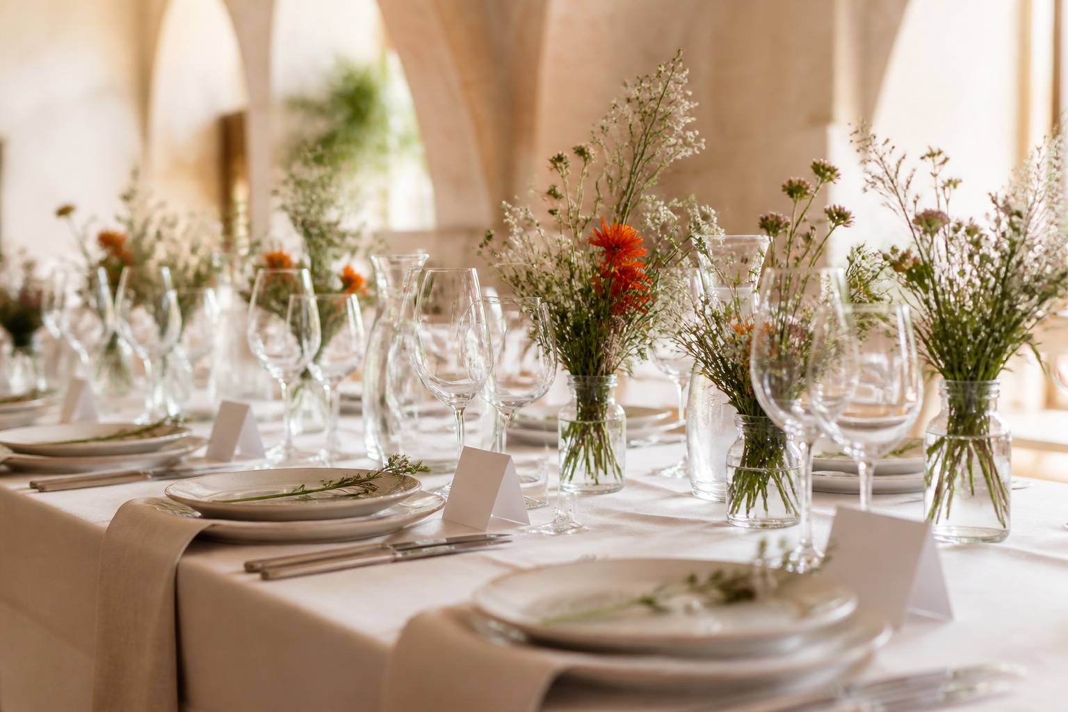 Table de réception dressée d'une nappe en lin crème avec fleurs des champs